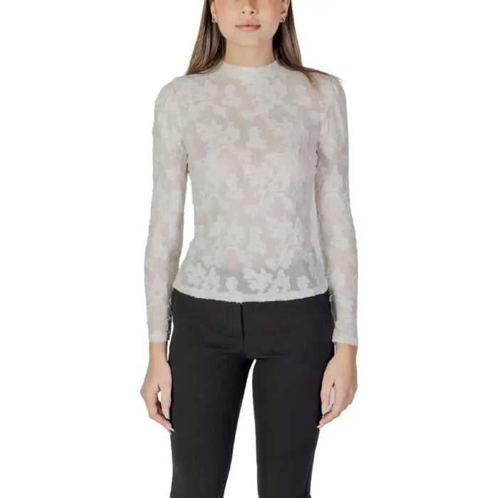Woman wearing a black floral lace long sleeve top and black pants