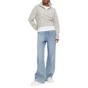 Woman wearing a gray knit quarter zip sweater and wide-leg jeans showcasing winter style