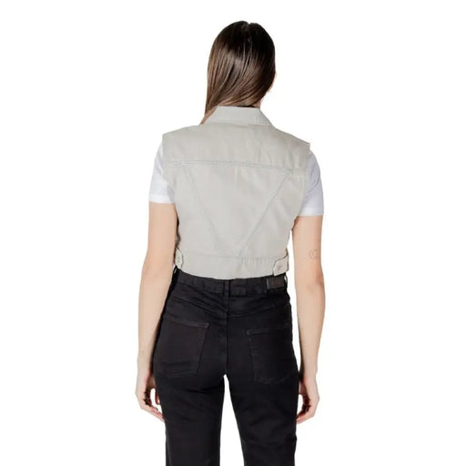 Woman wearing a light gray denim vest and black pants showcasing stylish casual attire
