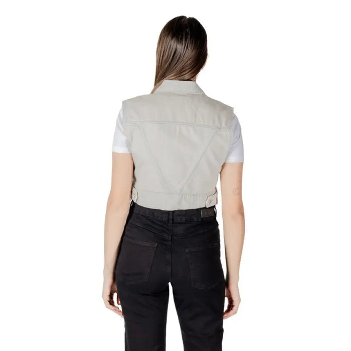Woman wearing a light gray denim vest and black pants showcasing stylish casual attire