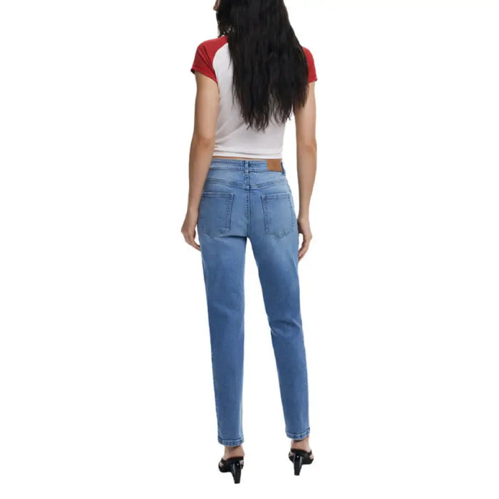 Woman wearing light blue denim jeans and a white T shirt with red sleeves