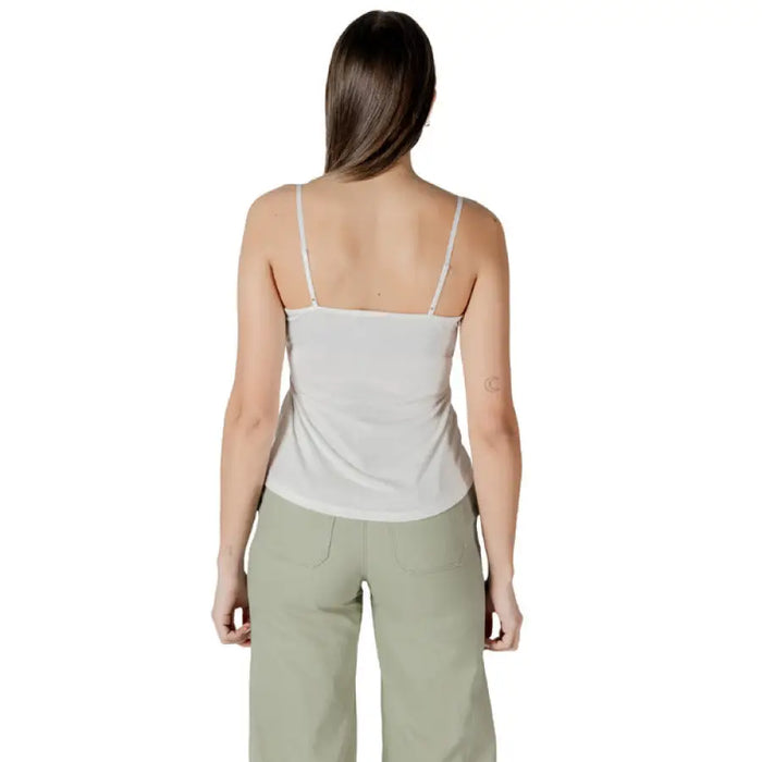 Woman in a light-colored camisole with white lace trim and green pants for women’s fashion