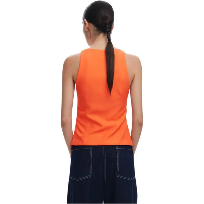 Woman wearing an orange floral print V neck top and dark blue pants