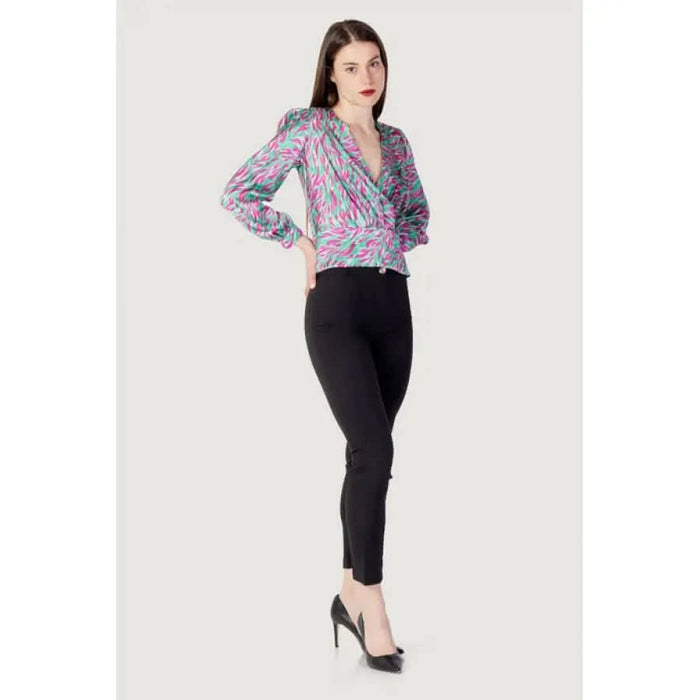 Woman models Rinascimento Women’s Green V-Neck Printed Blouse with black pants