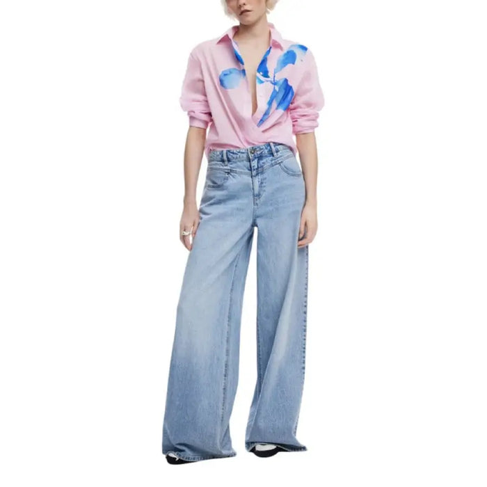 Woman wearing a pink floral print button-down shirt and wide-leg jeans