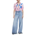 Woman wearing a pink floral print button-down shirt and wide-leg jeans