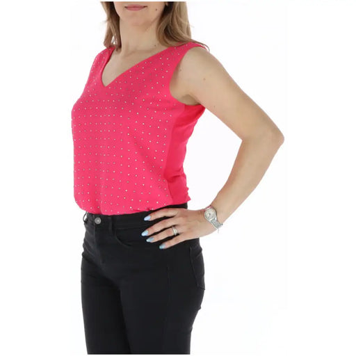 Woman wearing pink polka dot sleeveless top and black pants displayed in product image
