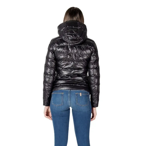 Woman wearing a shiny black hooded puffer jacket and blue jeans showcasing Women’s Black Hooded Puffer Jacket