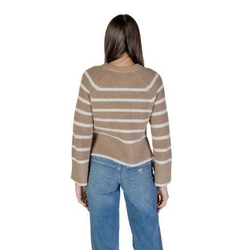 Woman in striped beige sweater and blue jeans showcasing Vila Clothes knitwear