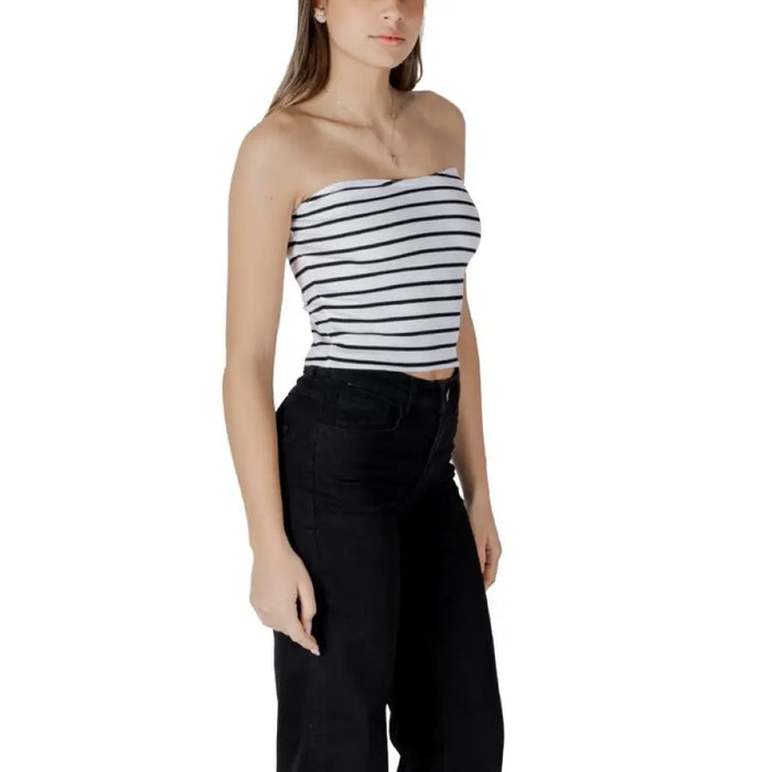 Woman wearing a striped tube top and black pants showcasing stylish casual attire