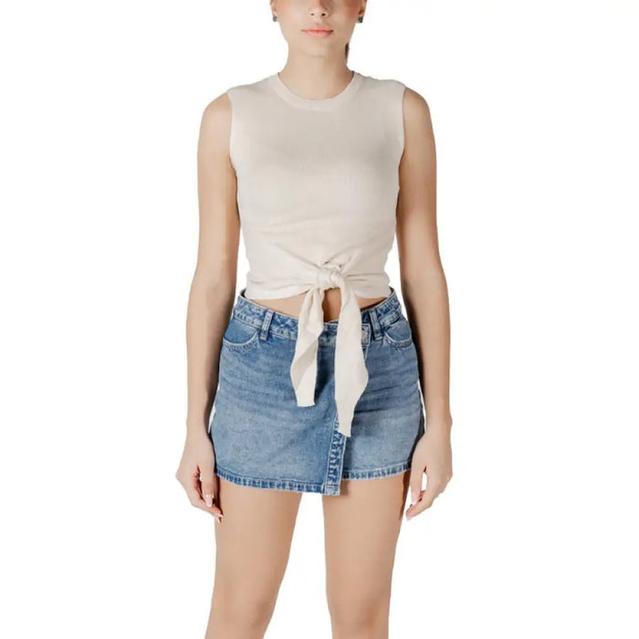 Woman wearing a beige tie-front tank top and denim mini skirt for Women’s Navy Collection