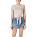 Woman wearing a beige tie-front tank top and denim mini skirt for Women’s Navy Collection