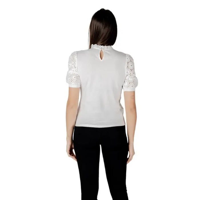 Woman wearing a white blouse with lace trim and black pants for the women’s fashion collection