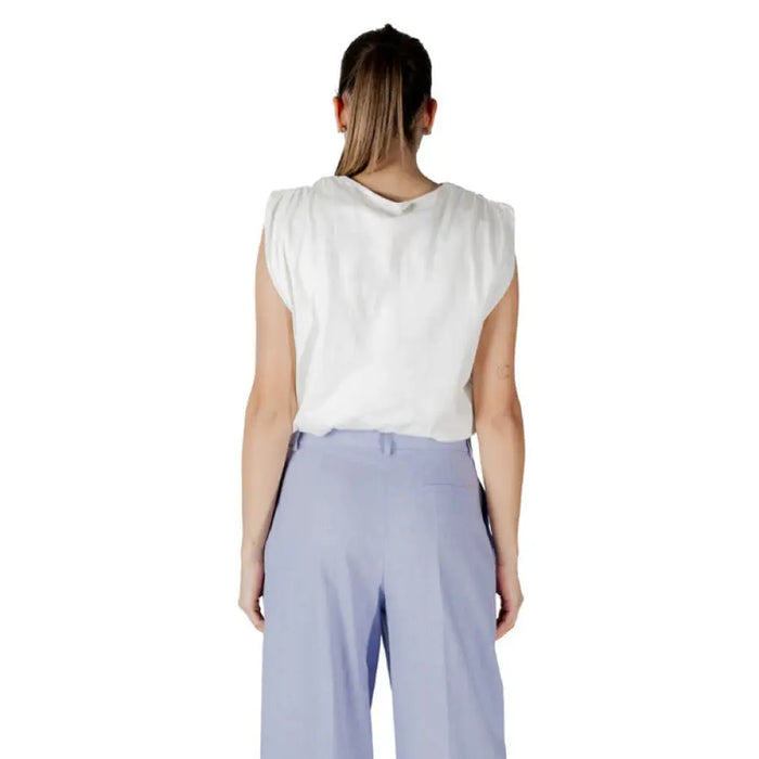 Woman wearing a white crop top and blue pants, showcasing fashionable women’s attire