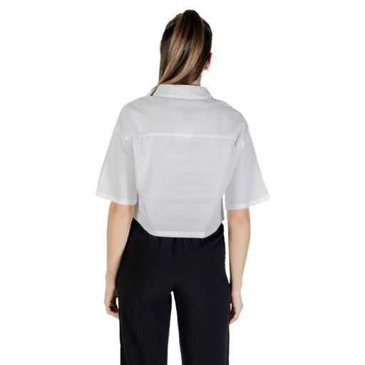 Woman wearing a white cropped button-down shirt and black pants for womens fashion display