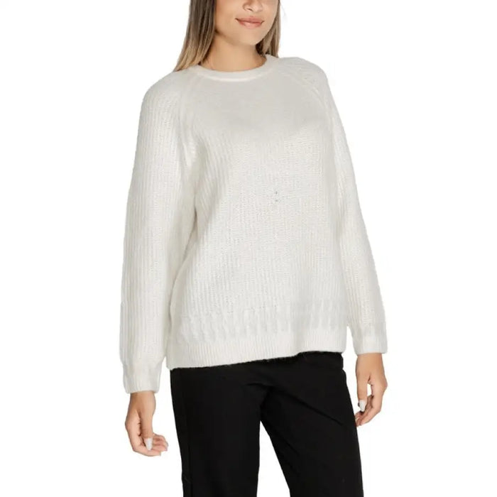 Woman wearing a white knit sweater paired with black pants showcasing stylish casual attire