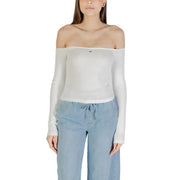 Woman wearing a white off-the-shoulder long-sleeved top and light blue pants