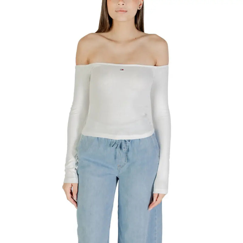Woman wearing a white off-the-shoulder long-sleeved top and light blue pants