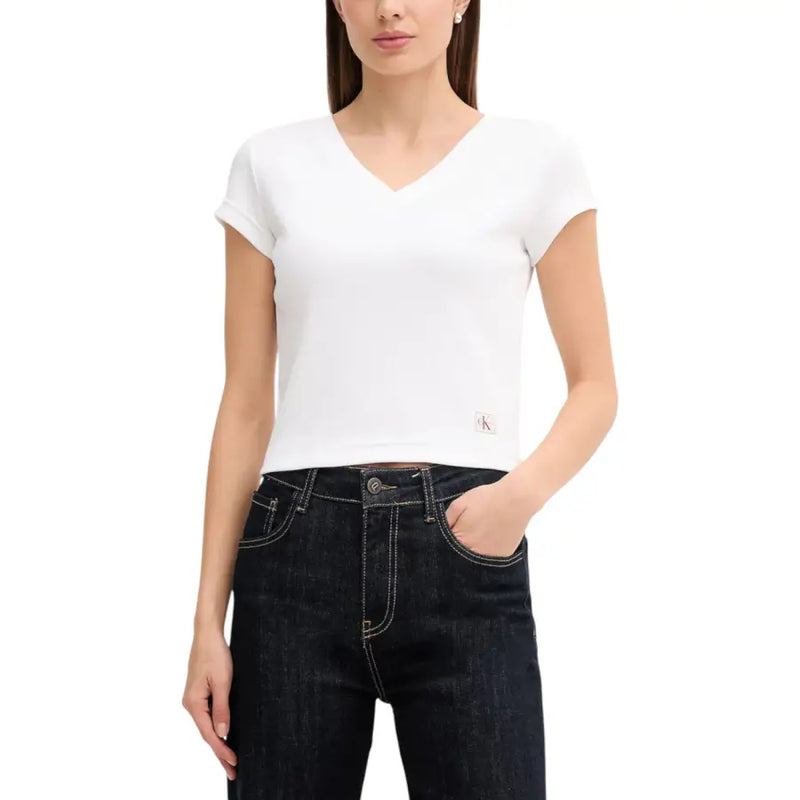 Woman wearing Calvin Klein Jeans white V neck short sleeve crop top and dark blue jeans