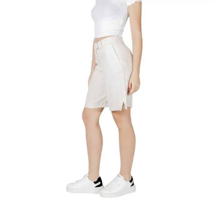 Woman wearing white sneakers and beige Bermuda shorts for women in a casual outdoor setting