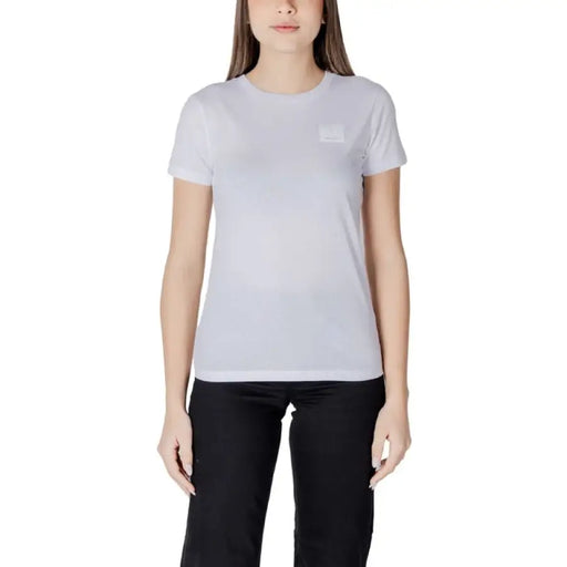 Femme portant un t-shirt noir à col rond, un t-shirt blanc et un pantalon noir sur un mannequin