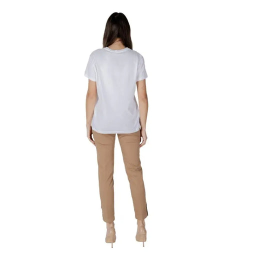 Woman wearing a white T-shirt with scooter graphic and tan pants