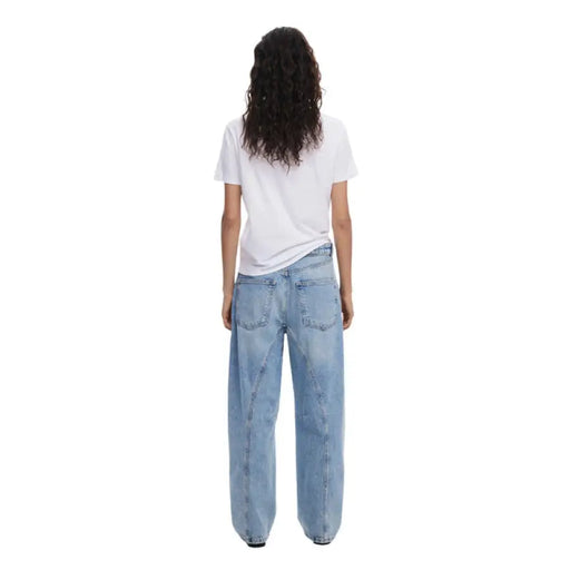Woman wearing white T shirt with colorful face graphic and light blue jeans