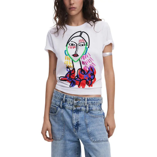 Woman wearing a white T shirt with a colorful face graphic and light blue jeans