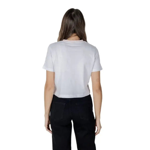 Woman wearing a white Guess T-shirt and black jeans showcasing casual fashion style