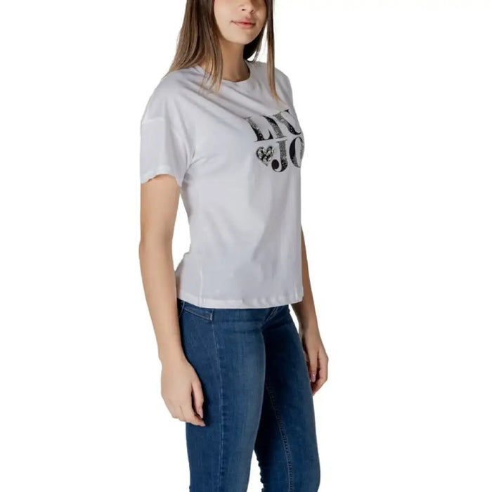 Woman wearing a white logo T-shirt and blue jeans for the Women’s White Logo T-Shirt product