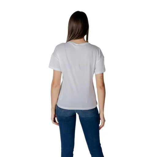 Woman wearing a white logo T-shirt and blue jeans for the Women’s White Logo T-Shirt product