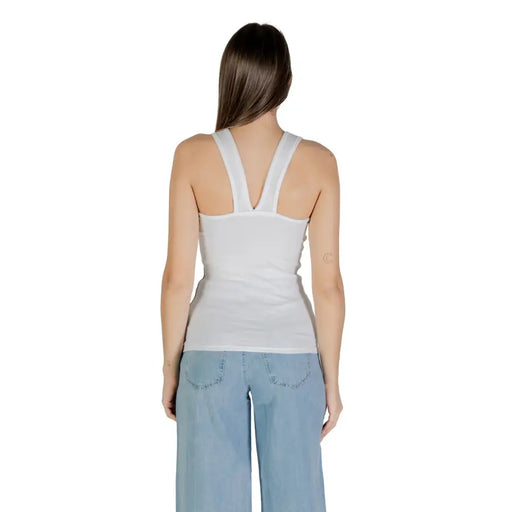 Woman modeling Calvin Klein Jeans white sleeveless round neck tank top with V-shaped shoulder straps and light blue wide-leg jeans