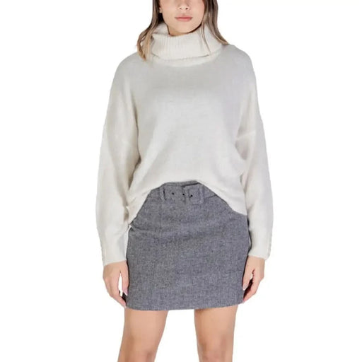 Woman in a white turtleneck sweater and gray skirt showcasing Ichi Women product