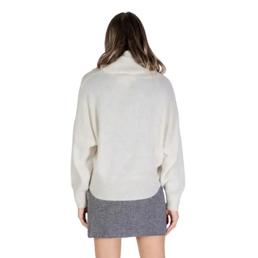 Woman in a white turtleneck sweater paired with a gray skirt from Ichi