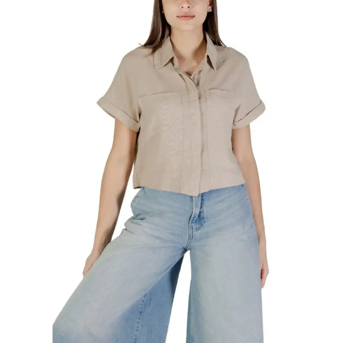 Woman wearing beige linen short-sleeved button-down shirt with wide-leg jeans for women