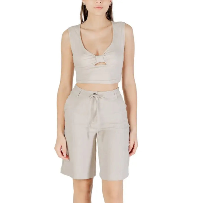 Woman wearing a beige two-piece outfit consisting of a crop top and pants
