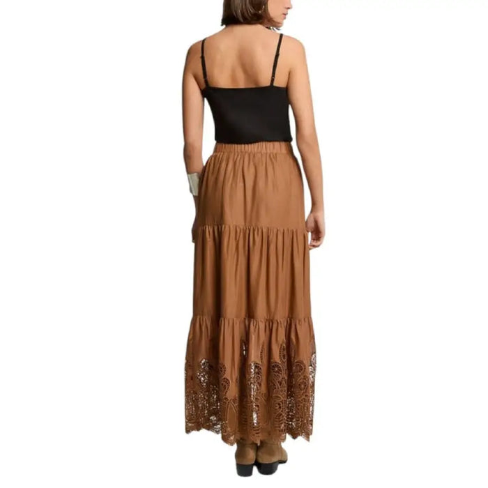 Woman wearing a black spaghetti strap tank top and a brown tiered maxi skirt
