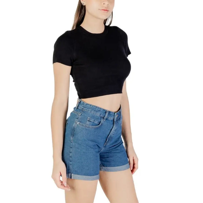 Woman wearing a black crop top and blue denim shorts, stylish summer outfit for women