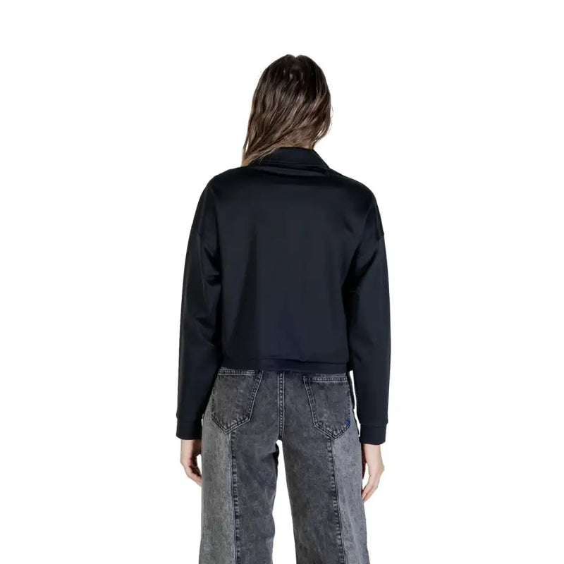 Woman wearing black cropped bomber jacket and two-tone gray wide-leg jeans