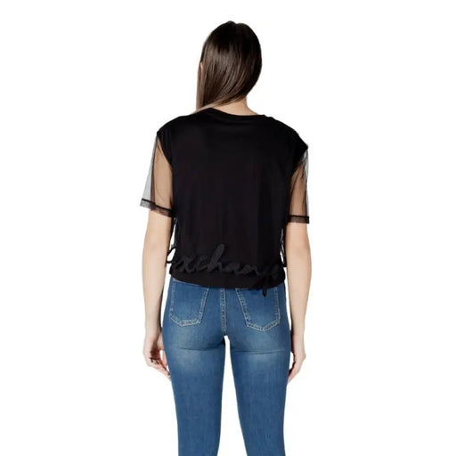 Woman wearing a Black T Shirt with Sheer Sleeves and Blue Jeans