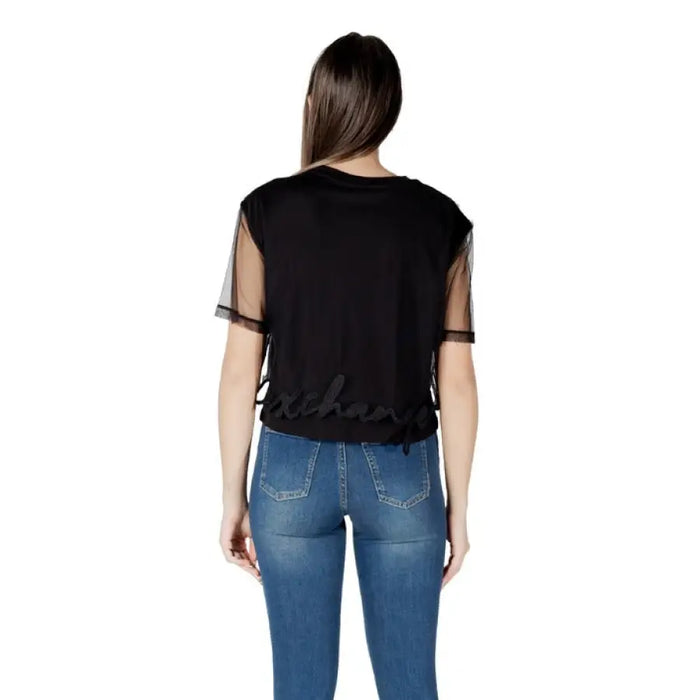 Woman wearing a Black T Shirt with Sheer Sleeves and Blue Jeans