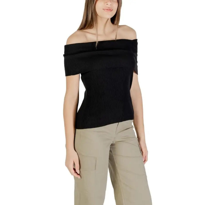 Woman wearing black off-the-shoulder ribbed top with khaki pants for stylish casual wear