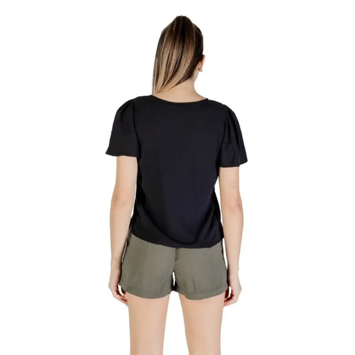 Woman wearing a black puff-sleeve V neck top and green shorts for casual style