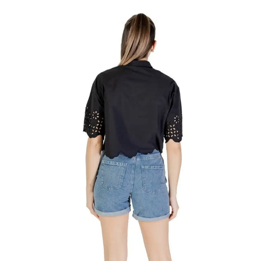 Woman wearing black scalloped-hem top and denim shorts for Women’s Black Eyelet Shirt and Denim Shorts