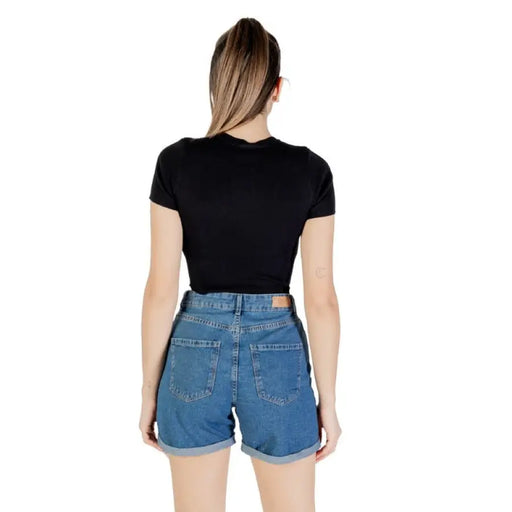Woman wearing a black crop top and blue denim shorts displayed in a product image