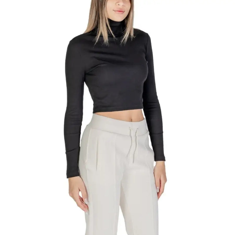 Woman wearing a black turtleneck crop top with light-colored sweatpants in a fashion photo