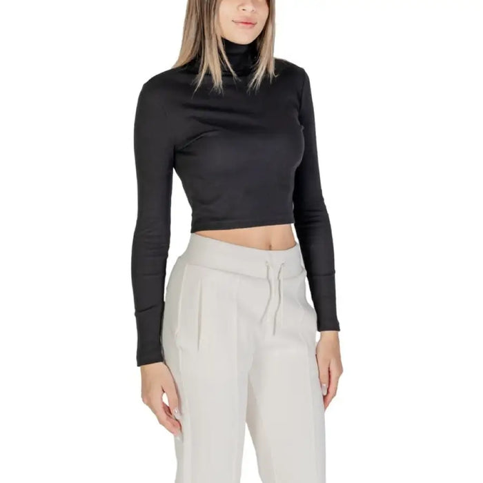 Woman wearing a black turtleneck crop top with light-colored sweatpants in a fashion photo