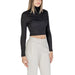 Woman wearing a black turtleneck crop top with light-colored sweatpants in a fashion photo