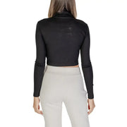 Woman wearing a black turtleneck crop top and light-colored sweatpants