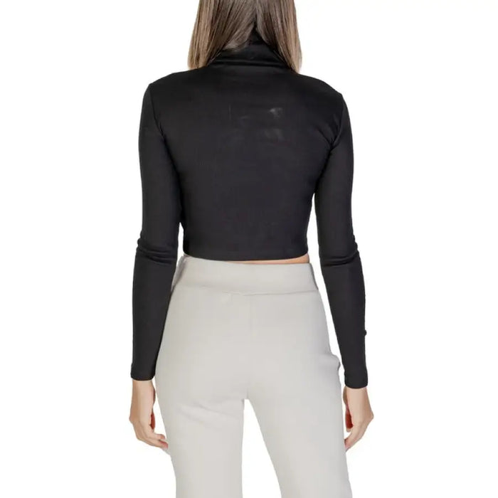Woman wearing a black turtleneck crop top and light-colored sweatpants